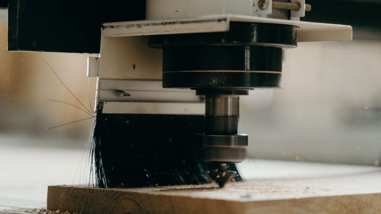 Wrzeciono centrum CNC z frezem i szczotką odpylającą podczas obróbki płyty